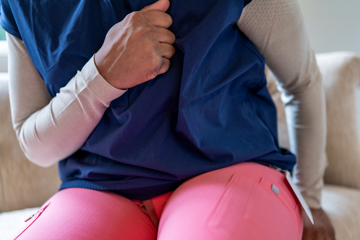 black woman wearing medical scrubs experiences chest pain