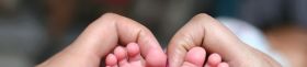 A Close-up of tiny baby feet and mother's hand fingers