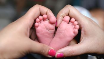 A Close-up of tiny baby feet and mother's hand fingers