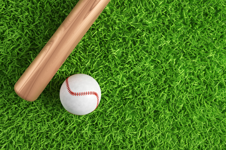 Baseball ball and bat on green grass