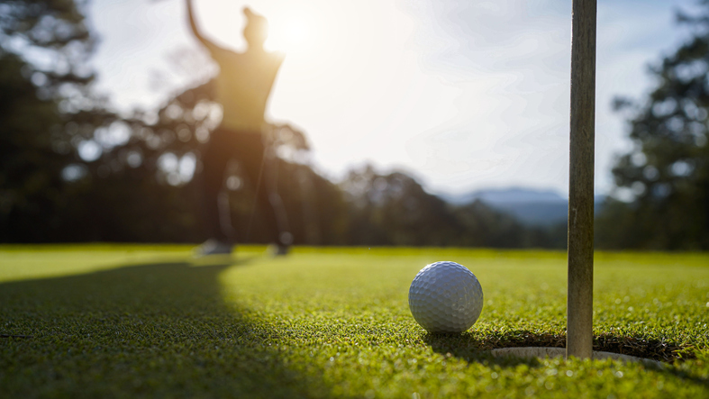 Blurred golfer playing golf in the evening golf course, on sun set evening time.