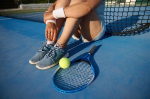 Tennis player sitting on court with racket and ball