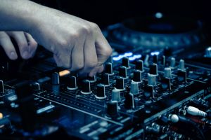 close up of DJ hands on dj console mixer
