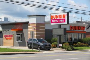 A car exits a Dunkin' drive thru. Dunkin' is the largest...