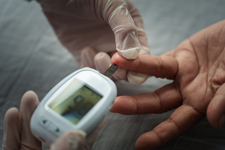 doctor using glucometer checking blood sugar level of senior woman. diabetes concept