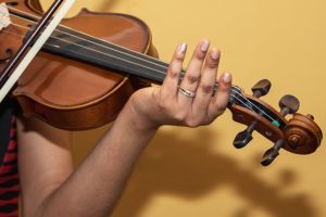 violin close up, african woman playing, yellow wall background