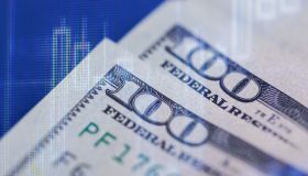Close-up view of one hundred dollar bills with financial graph overlay