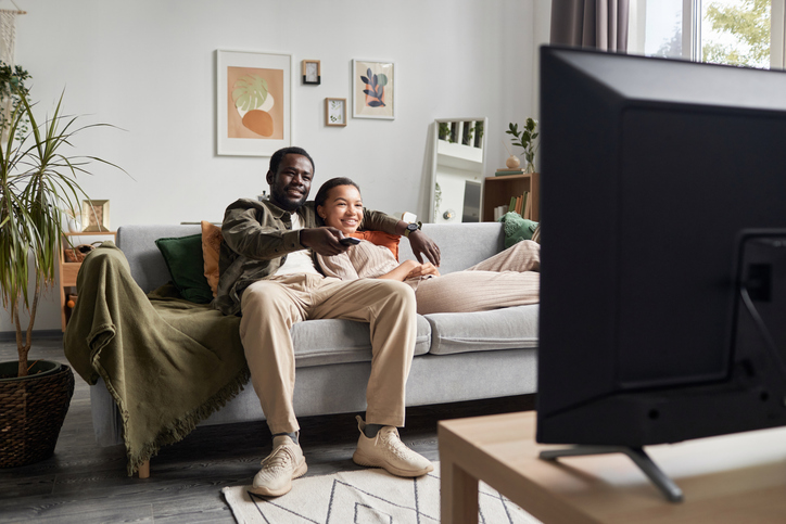 Young Black couple watching Tv together in cozy home