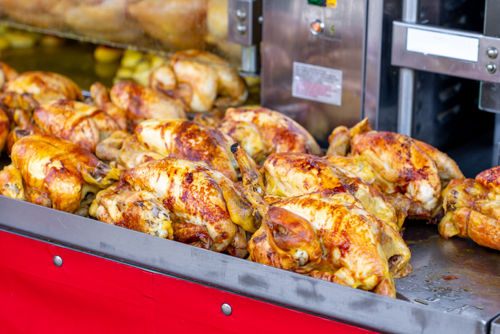 A market stall features an industrial grill oven that cooks whole chickens