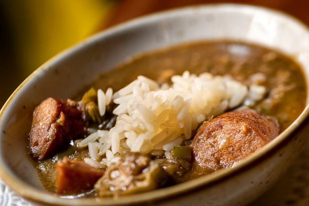 A bowl of hearty stew with chunks of meat, vegetables, and white rice.
