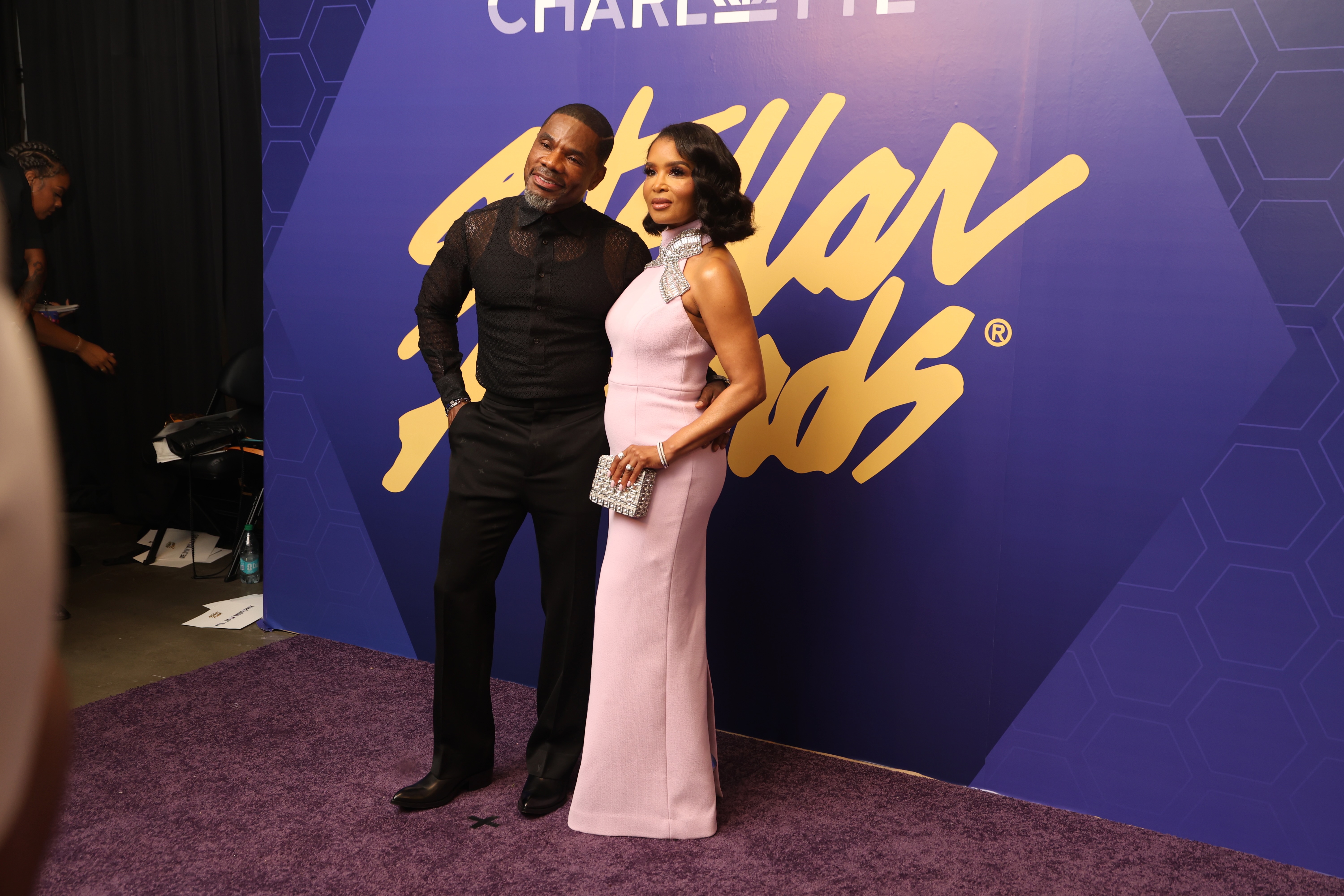 Two people posing in front of a large "Charleyhd" logo backdrop at an event.