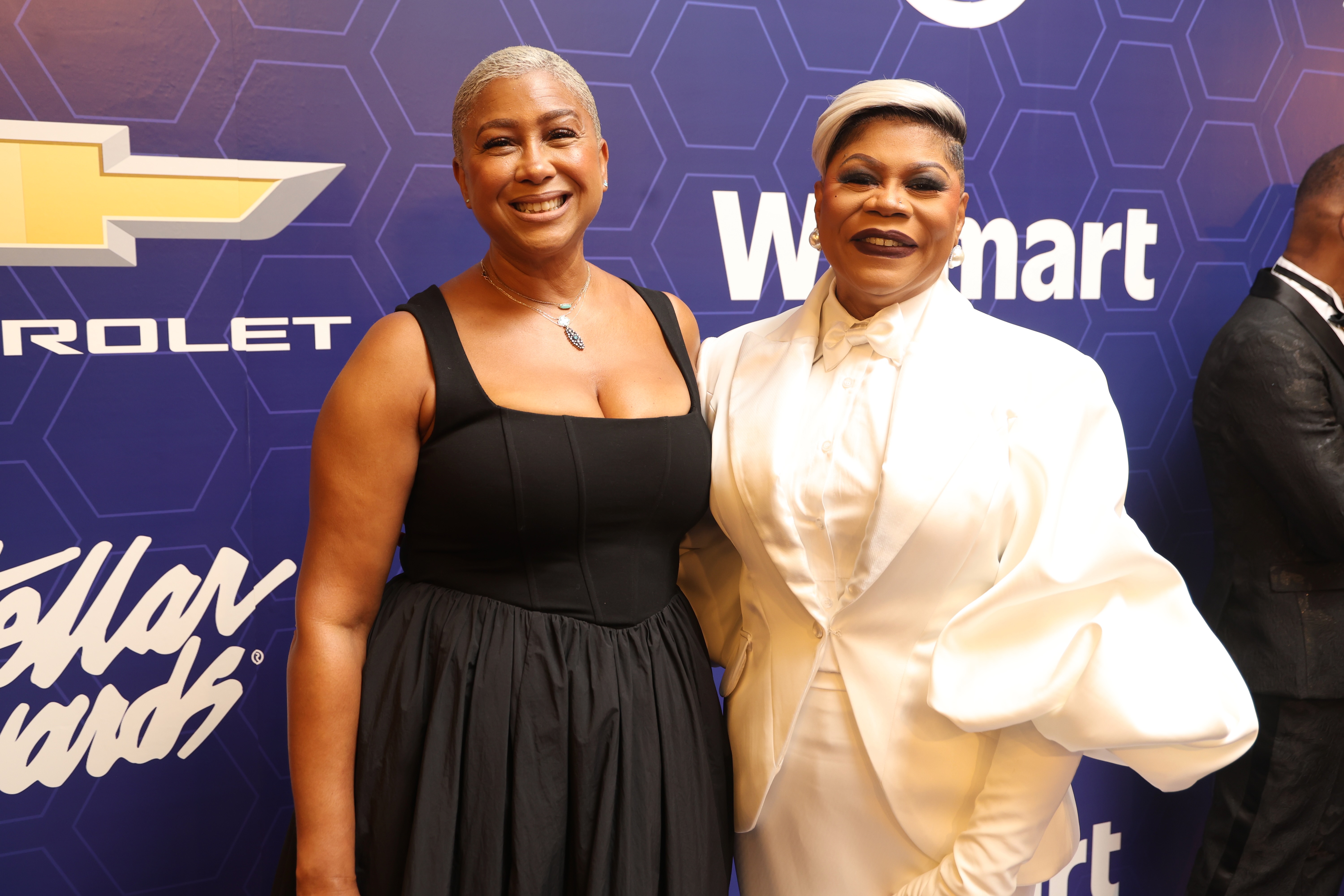 Two smiling Black women posing together in front of a Walmart logo and Chevrolet branding.