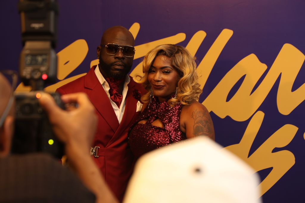 Two people posing for a photo at an event, a man in a red suit and a woman in a red sequined dress.